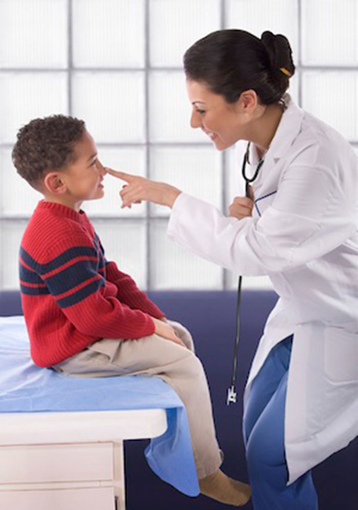 Doctor touching happy boy patient on nose during exam
